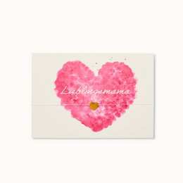 A pink heart-shaped card with the text "La meilleure maman" (The best mom) written inside. The card appears to be a friendship or Mother's Day card.