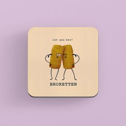Circular coaster with a playful illustration of two broccoli florets holding hands, accompanied by the text "Broketten". The coaster appears to be made of a light-colored material, possibly wood or cardboard.