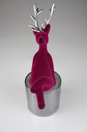  A plush, fuchsia-colored deer figurine with silver antlers, standing in a metal container.