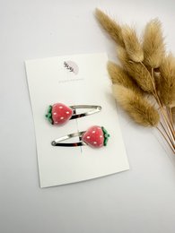 Set of 2 hair clips in silver and gold colors, featuring a bow design with pom-pom accents, suitable for kids' hairstyles.