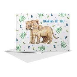 A hand-painted greeting card featuring a cute lion cub surrounded by tropical leaves and the text "Thinking of you". The card is A6 size and part of the Friendship Cards collection.