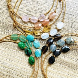 Adjustable bracelet with natural stones in various colors including green, blue, and yellow. The bracelet features a mix of round, oval, and irregular shaped stones in a gold-toned metal setting.