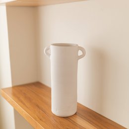 Tall, cylindrical vase in black, white, and terracotta colors. Minimalist, modern design suitable for home decor.