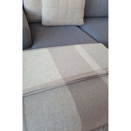 A large, soft, gray and white striped blanket or throw with a fringed edge. The blanket appears to be made of a cozy, woven material and would be suitable for use as a decorative accent piece or for keeping warm.